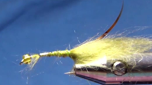 The fly now has a sparse olive tail made from Wilson Fuzzle Dub tied at the bend, and a strand of gold mylar tinsel secured along the near side of the hook with the silver side facing up.