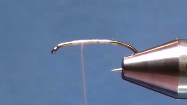 Fly secured in the vice, showing the hook shank evenly covered with a smooth cream thread base.