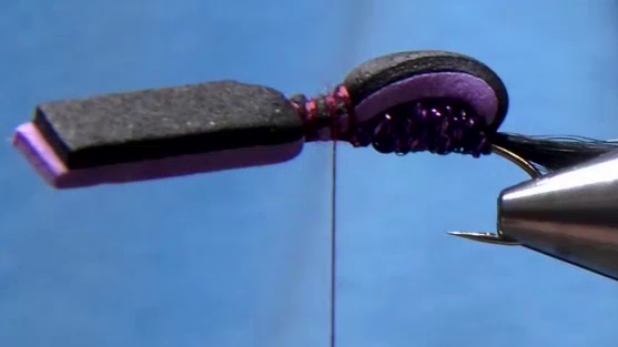 The thread is advanced to the hook eye, the foam is tied down again to form the head, and then the thread is wrapped back to the thorax area, leaving an open space for legs and hackle.
