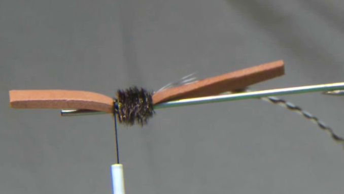 Peacock herl and grizzly hackle are tied in securely at the post, ready for wrapping to build the segmented body profile.