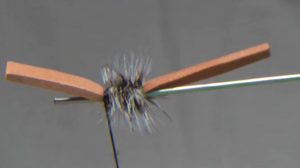 Peacock herl is wrapped along the post to form a glossy segmented body, building volume and taper.