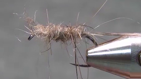 Fly hook with silver wire secured along the shank and a natural Hare’s Ear dubbed body forming the fly.