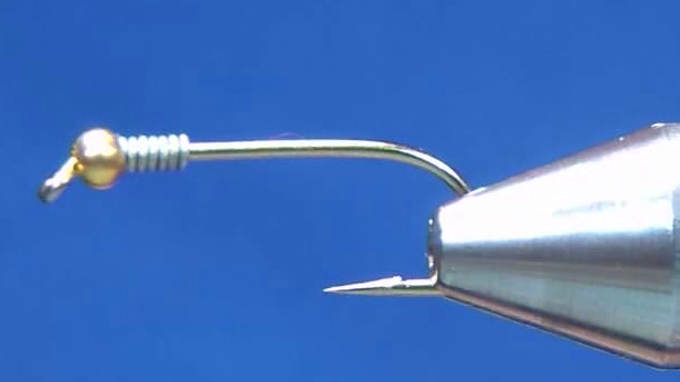 A hook is fitted with a bead and wire, which are secured in place before the hook shank is covered with tying thread.